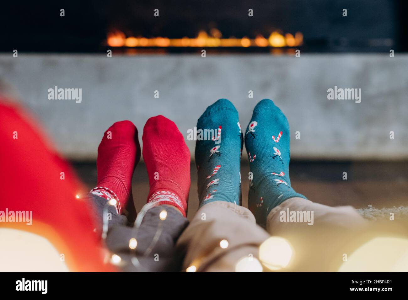 noël coziness sur le fond d'une cheminée électrique, un couple en chaussettes rouges et vertes avec une guirlande, minimalisme Banque D'Images