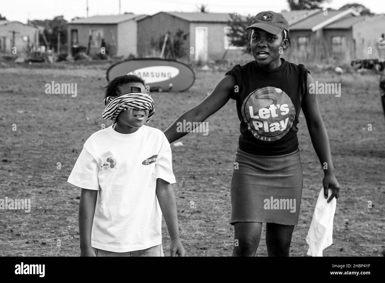 JOHANNESBURG, AFRIQUE DU SUD - 12 août 2021 : entraîneur bénévole de football travaillant avec de jeunes enfants africains sur le terrain de jeux de l'école Banque D'Images