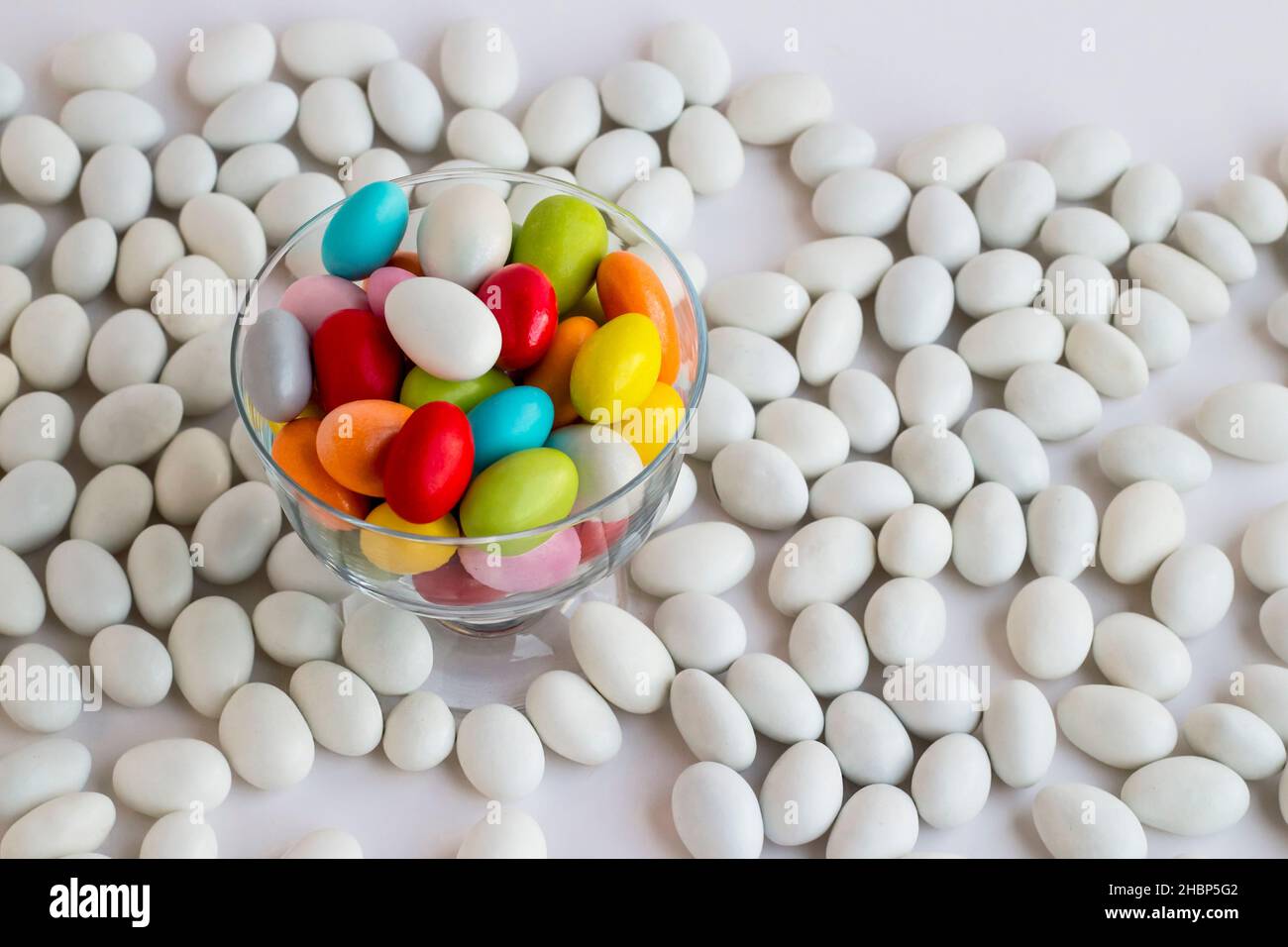 Bonbons traditionnels turcs aux amandes colorées enrobées dans le bol en verre transparent sur les autres amandes de couleur blanche. Image conceptuelle pour les célébrations. Banque D'Images