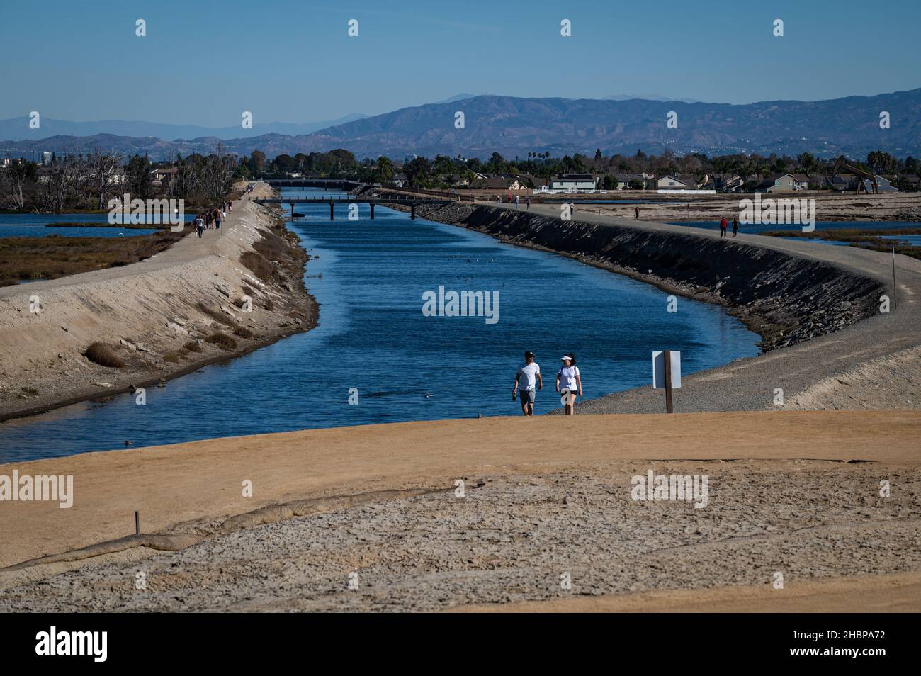 Les gens qui marchent près du canal de Wintersburg, qui canalise les eaux pluviales et les eaux de ruissellement urbaines jusqu'à la zone humide de Bolsa Chica. Banque D'Images