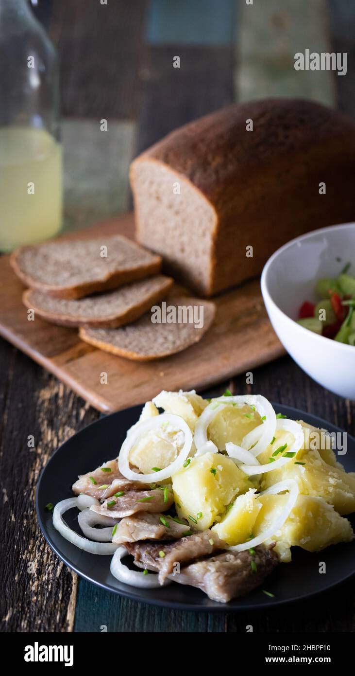Pain de seigle fait maison en tranches avec une assiette de pommes de terre et de hareng.Salade et sauce.Vue avant. Banque D'Images