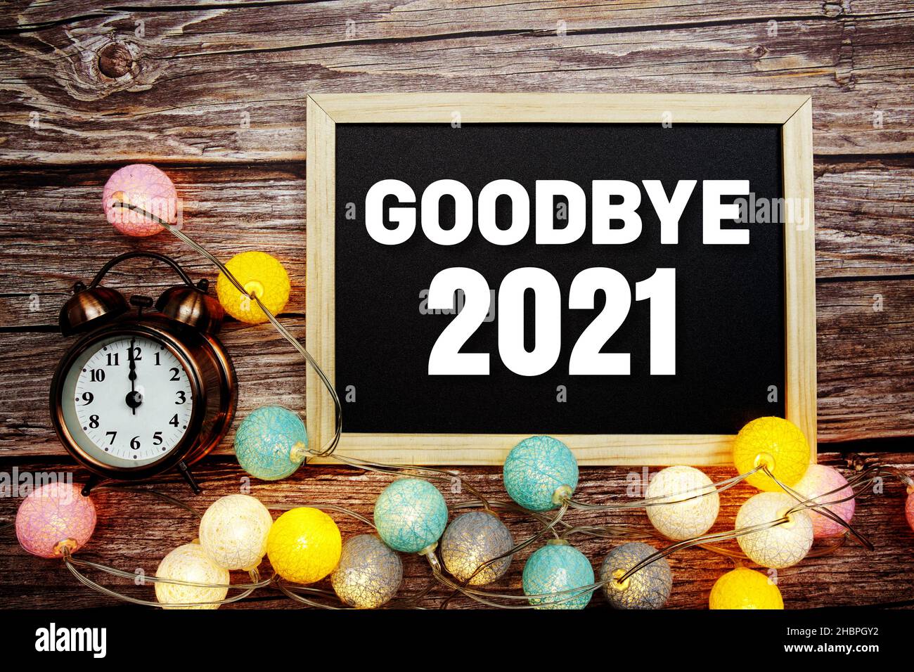 Au revoir 2021 texte sur tableau noir en bois avec réveil et décoration de boules de coton LED sur fond de bois Banque D'Images