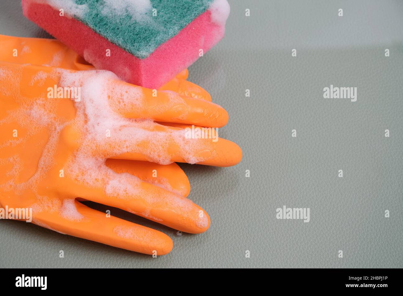 Gants avec éponge humide pour le nettoyage sur verre recouvert de mousse Banque D'Images