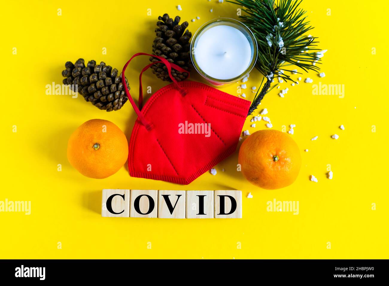 Les mandarines sont dans le masque médical parmi les branches de l'arbre de Noël, mot Covid cubes en bois Banque D'Images