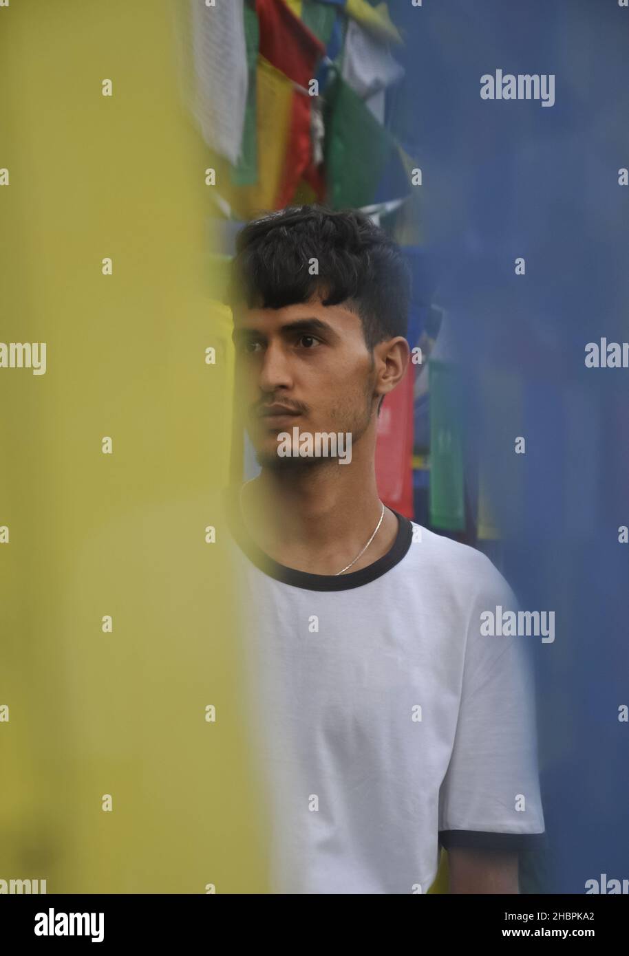 Foyer sélectif d'un jeune indien regardant latéralement tout en se tenant autour des drapeaux de prière bouddhistes Banque D'Images