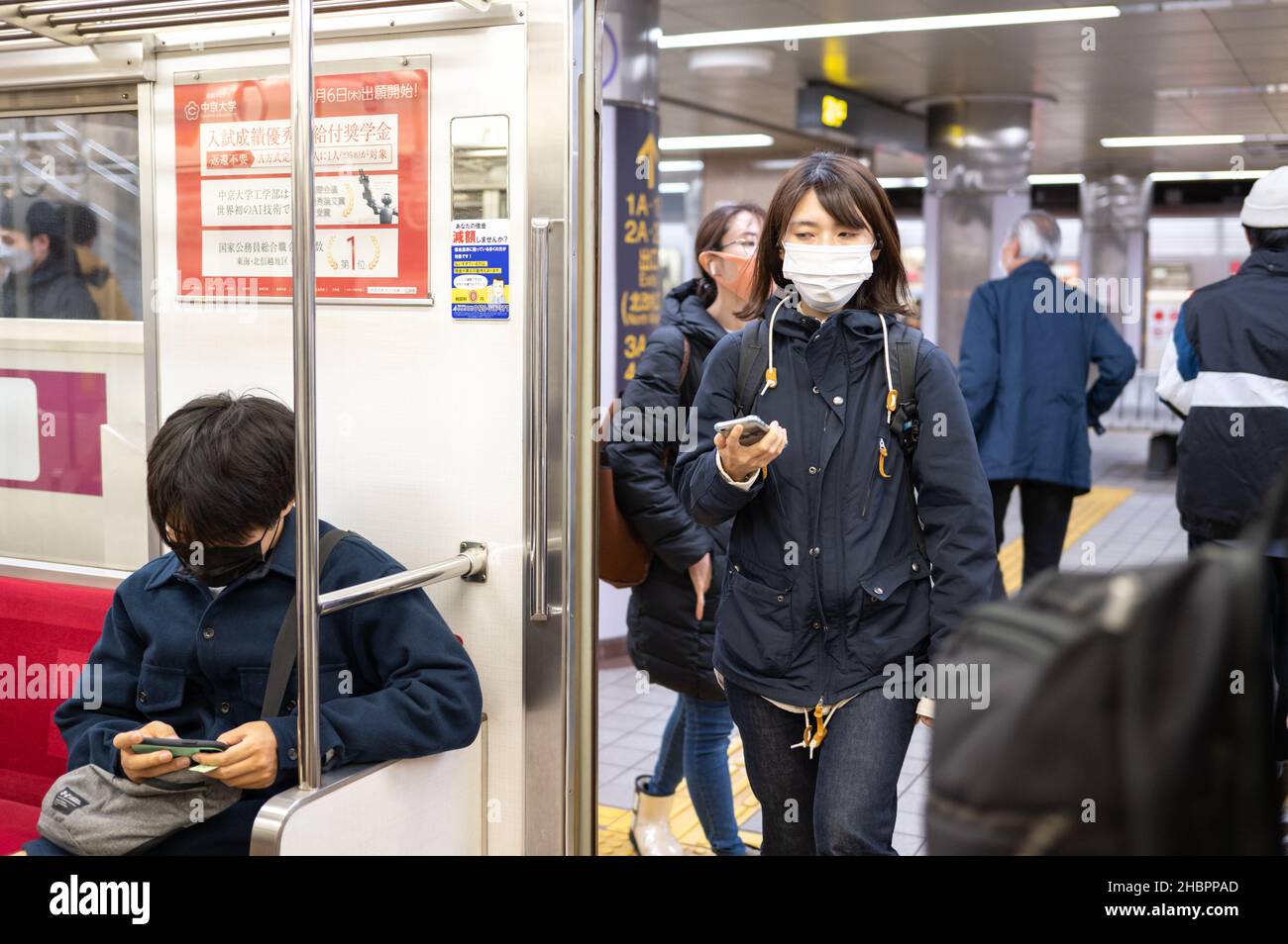 Navetteurs dans le métro avec des smartphones, une femme portant des masques entrant dans la voiture.Restrictions Covid-19. Banque D'Images