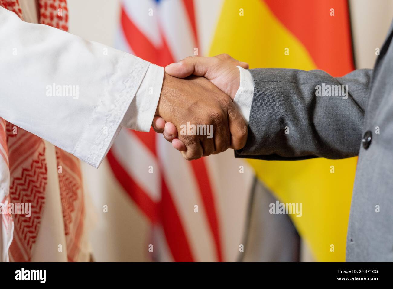 Poignée de main des partenaires politiques interculturels ou des délégués étrangers contre les drapeaux lors d'une conférence ou d'un sommet Banque D'Images