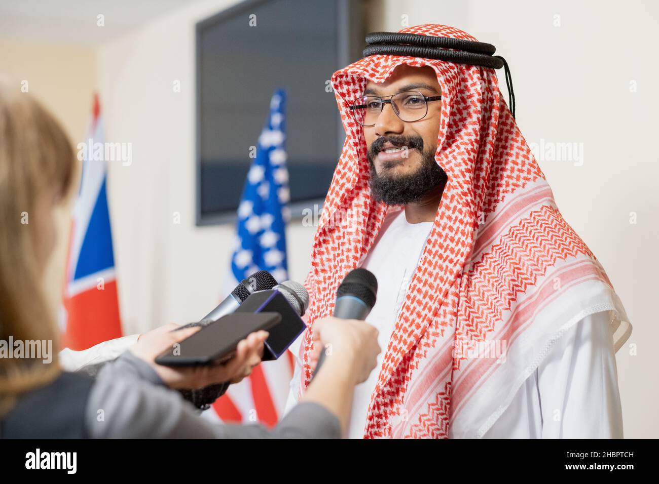 Jeune homme d'affaires arabe vêque de vêtements nationaux, qui donne une interview aux journalistes après un événement politique dans la salle de conférence Banque D'Images