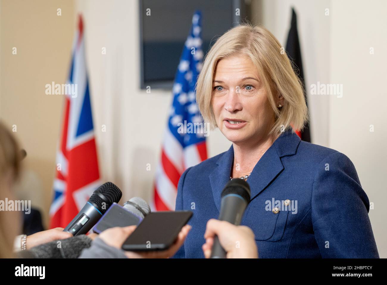 Femme mature députée en costume élégant parlant dans les microphones des journalistes à la conférence de presse après un événement politique Banque D'Images