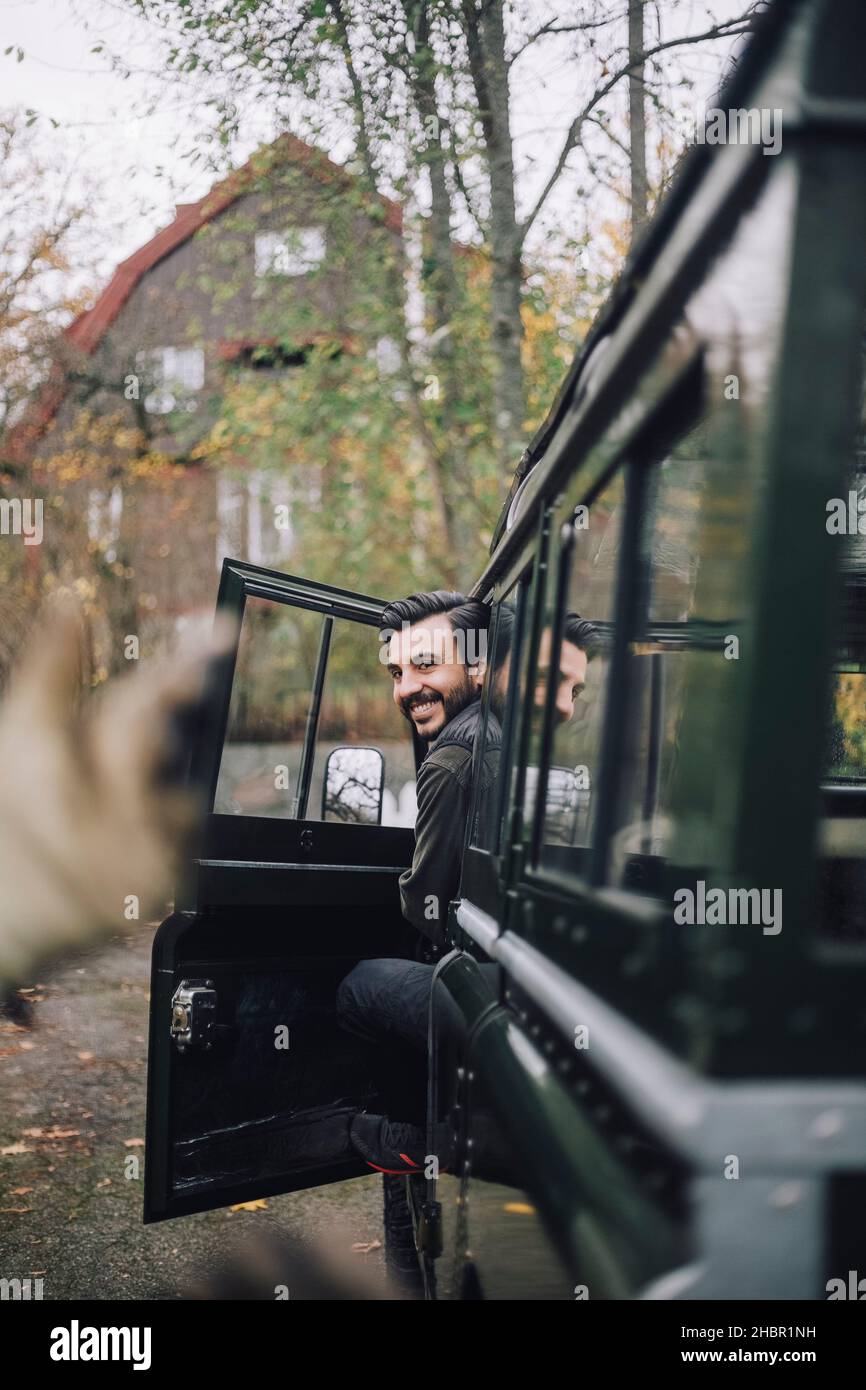 Homme souriant ouvrant la porte d'un véhicule utilitaire sport Banque D'Images