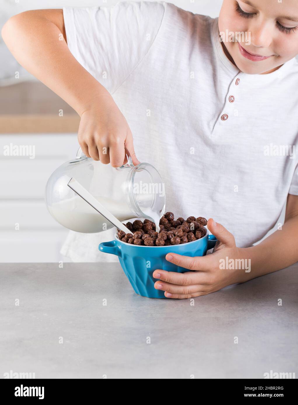 Un enfant verse du lait dans un pot dans un bol de flocons de  chocolat.Concept petit déjeuner Photo Stock - Alamy