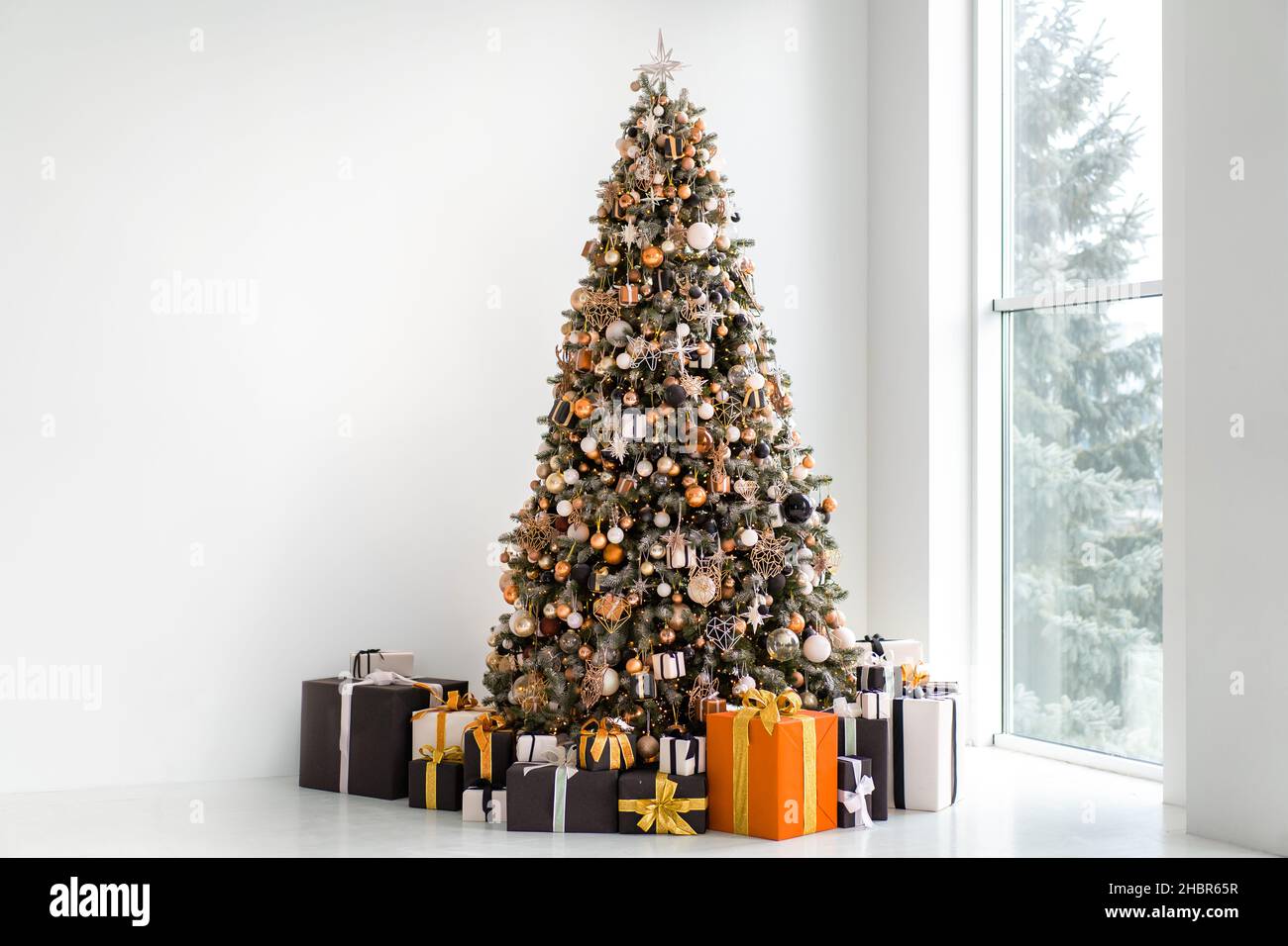 Sapin de Noël à l'intérieur blanc avec boîte cadeau élégante noire et orange.Minimalisme.Fond de mur blanc.Espace libre pour le texte.Décoration moderne CHRI Banque D'Images