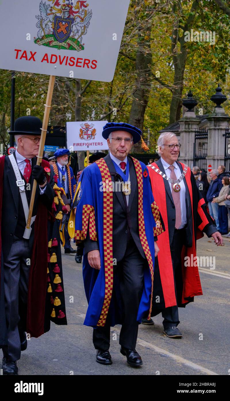 Des hommes défilent dans le Lord Mayor’s Show 2021, Londres, Angleterre, avec les compagnies modernes de la Livery tenant des conseillers fiscaux et des panneaux de pompiers. Banque D'Images