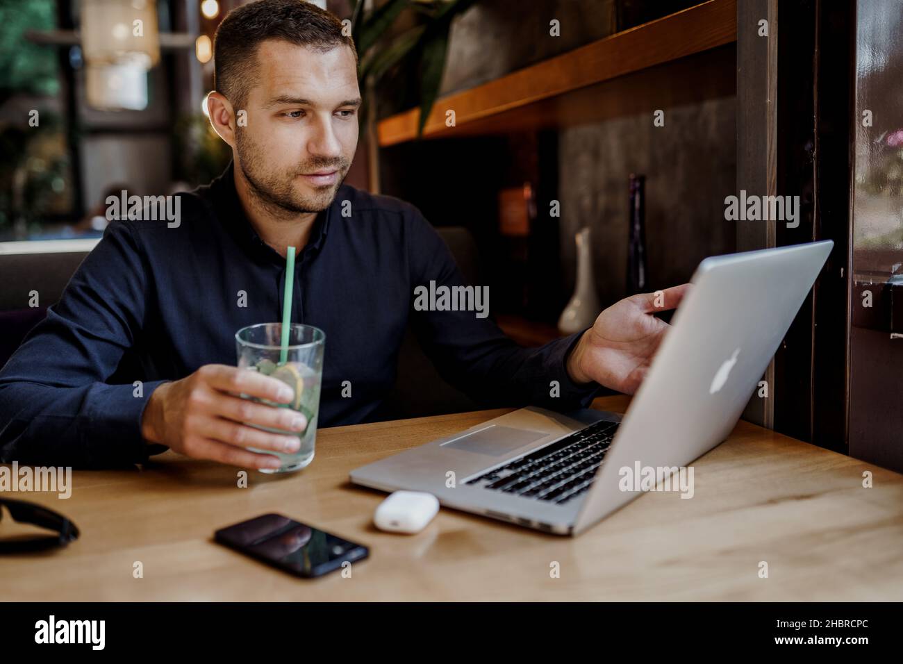 Un jeune homme d'affaires a une réunion en ligne sur ordinateur portable au restaurant.Travail à distance. Banque D'Images