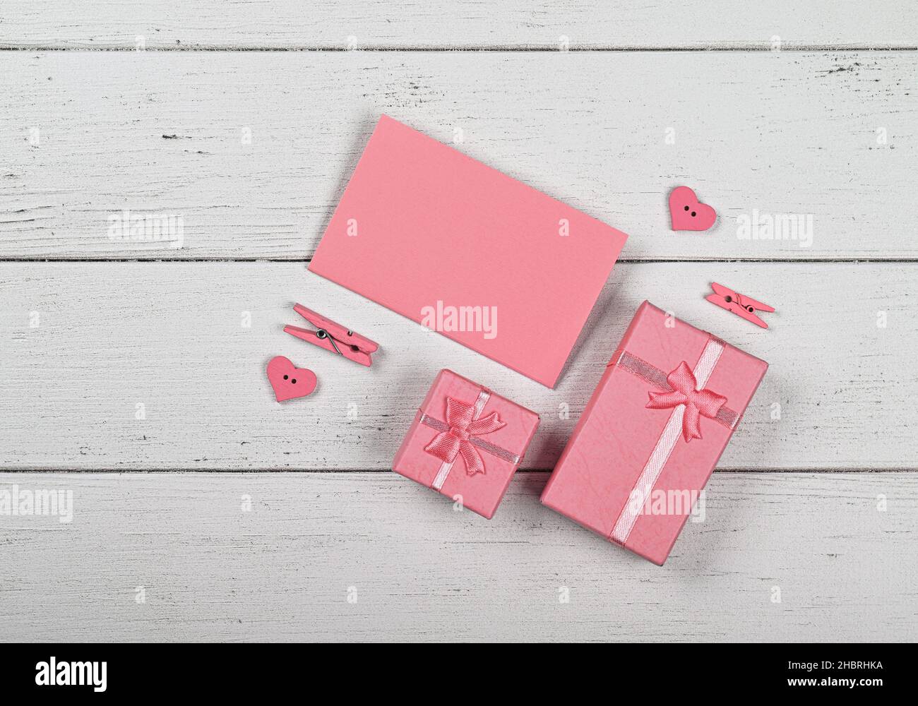 Modèle de boîte cadeau rose pour la Saint-Valentin avec noeuds en mousseline et note en papier sur fond de table en bois blanc, pose à plat rapprochée, vue du dessus en hauteur, Banque D'Images