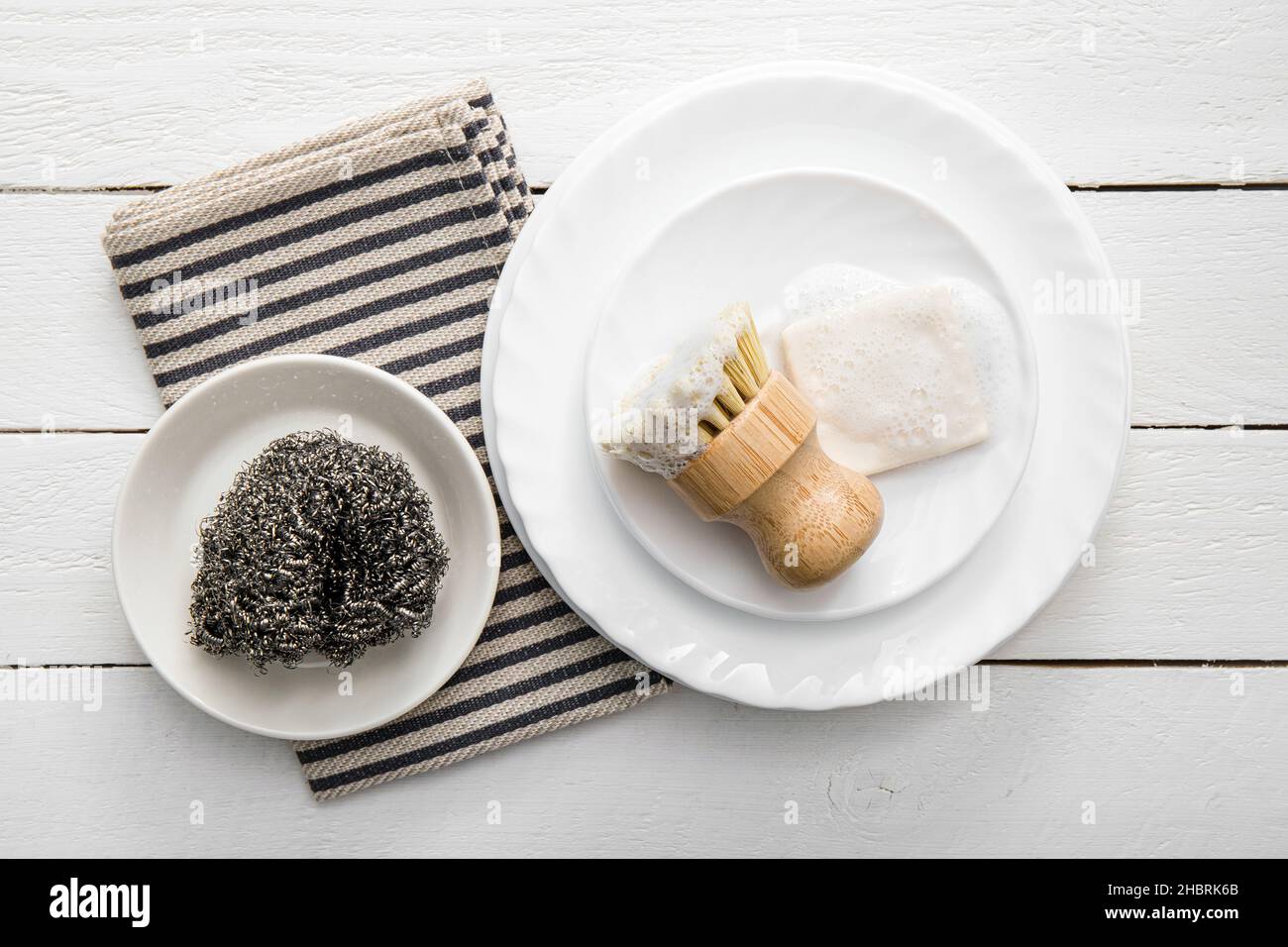 Savon à vaisselle solide, recouvert de mousse.Un style de vie sans gaspillage.Savon lave-vaisselle sur pile de plaques avec brosse en sisal mousseuse pour la cuisine. Banque D'Images