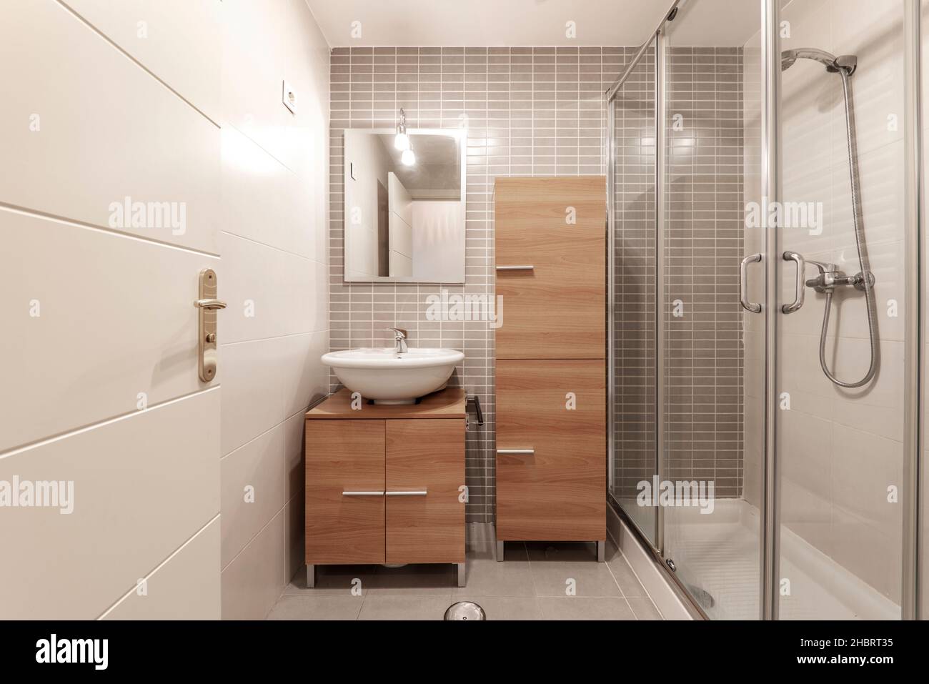 toilettes en merisier avec placard et meuble-lavabo avec douche et miroir rectangulaire Banque D'Images