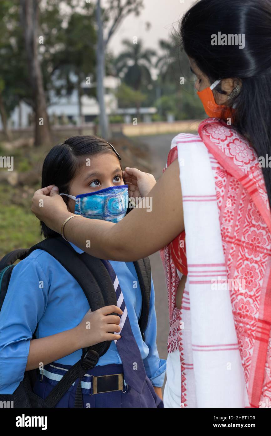 Une jeune fille d'école indienne va à l'école à nouveau après une pandémie avec sa mère portant un masque de protection Banque D'Images