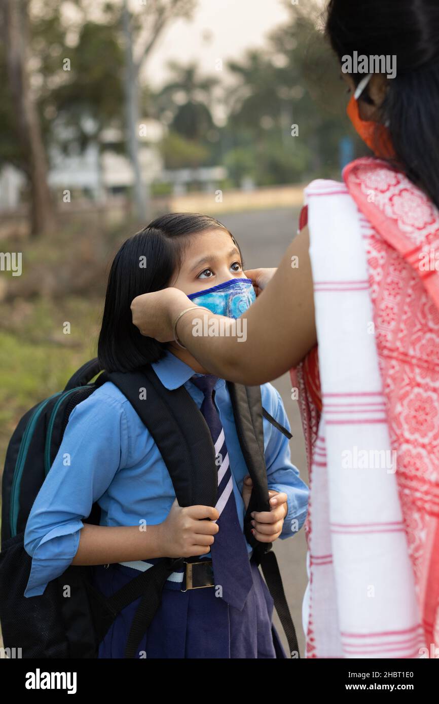 Une jeune fille d'école indienne va à l'école à nouveau après une pandémie avec sa mère portant un masque de protection Banque D'Images