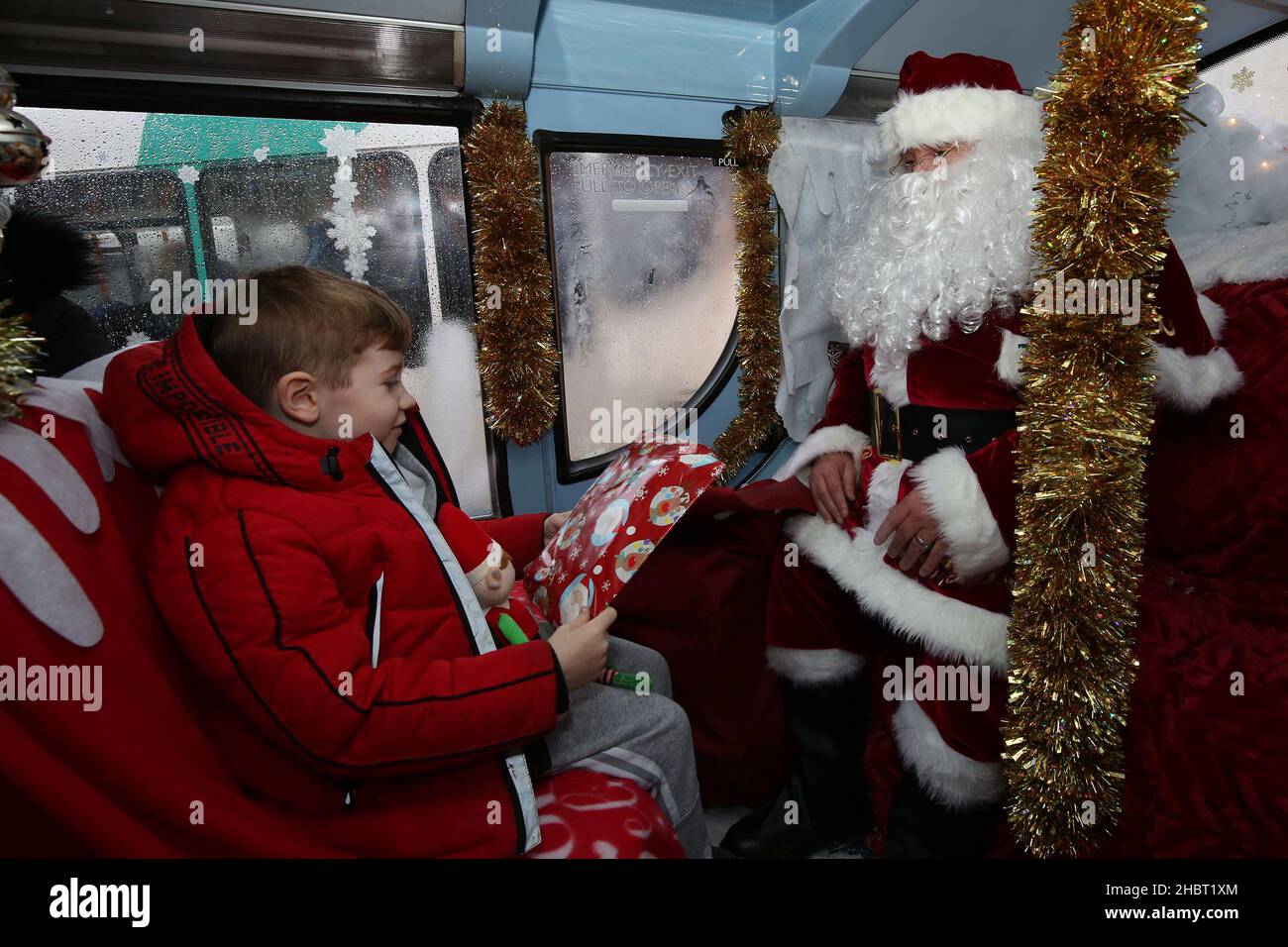 Ayr, Ayrshire, Écosse : les bus Stagecoach Santa viennent en ville par un bus Stagecoach à la gare routière d'Ayr. Le bus ouvert a été aménagé comme une grotte.Le véhicule a été transformé en un pays merveilleux pour l’hiver pour un week-end seulement avec le Père Noël et ses elfes qui ont mis en place une grotte de fortune, et dans le processus de collecte de £185 dons pour la charité des enfants, le bus sensoriel d’Aoife.Dans la grotte gratuite socialement distancée du dépôt d'Ayr Stagecoach, les enfants ont dit à Santa ce qu'ils veulent pour Noël avant de recevoir un cadeau.Le père Noël remet un cadeau à un enfant Banque D'Images