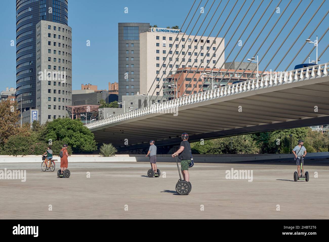 Touristes à cheval Segs Segway scooters électriques dans la Cité des Arts et des Sciences de Valence sous le pont Azul de Oro, Espagne Banque D'Images