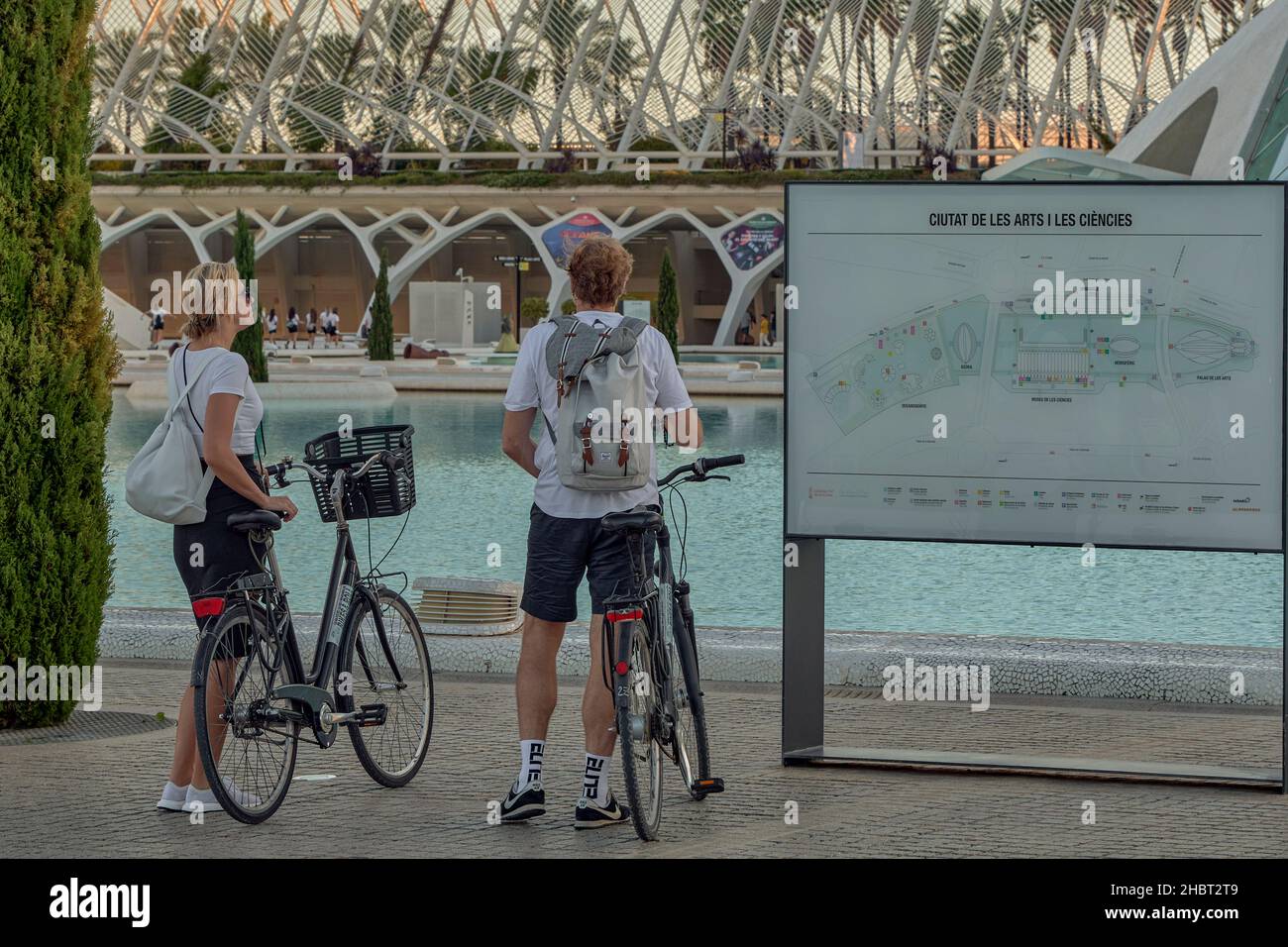 Couple d'hommes blonds et de femmes touristes avec un sac à dos sur leur dos sur un vélo regardant la carte de la ville des Arts et des Sciences, Valence Banque D'Images