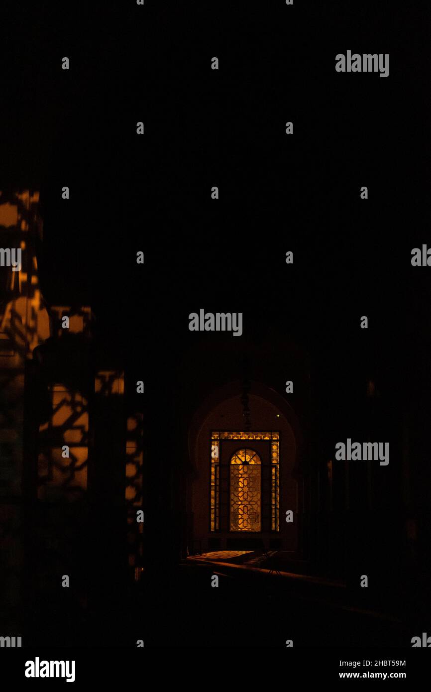 Un cliché vertical de la lumière qui brille à travers une fenêtre modèle du Moyen-Orient dans l'intérieur sombre Banque D'Images