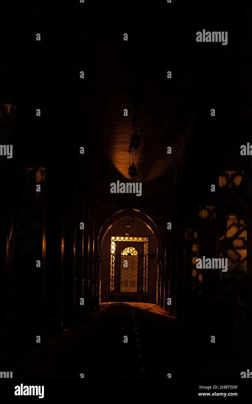 Un cliché vertical de la lumière qui brille à travers une fenêtre modèle du Moyen-Orient dans l'intérieur sombre Banque D'Images