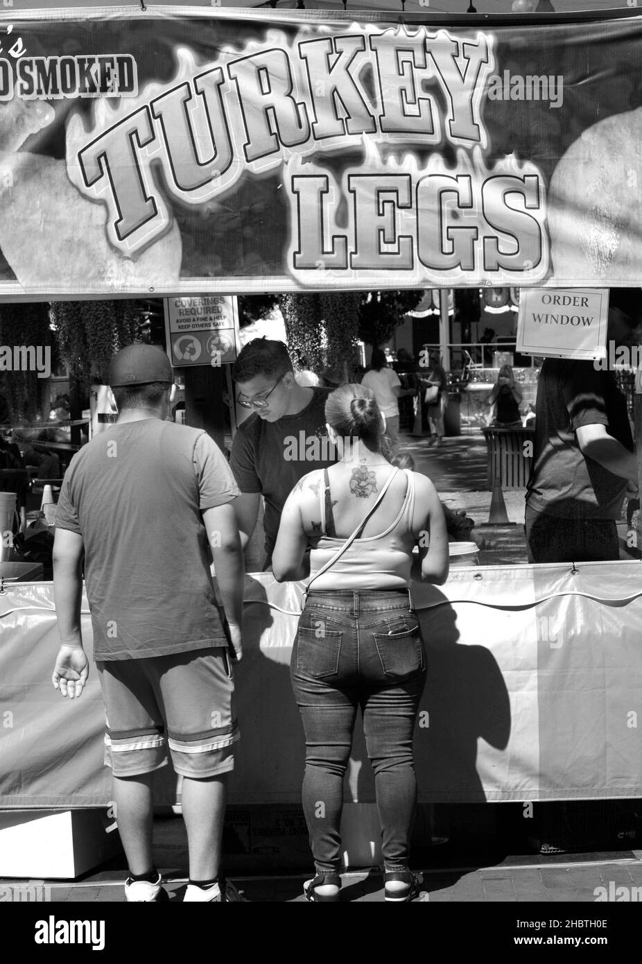 Un couple achète des pattes de dinde fumées à un vendeur de nourriture lors d'un festival en plein air à Santa Fe, Nouveau-Mexique. Banque D'Images