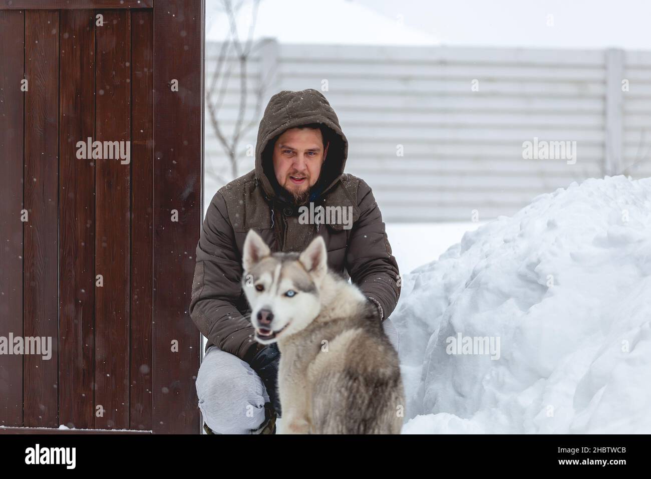 homme s'amusant avec son chien de compagnie husky sibérien dans la neige Banque D'Images