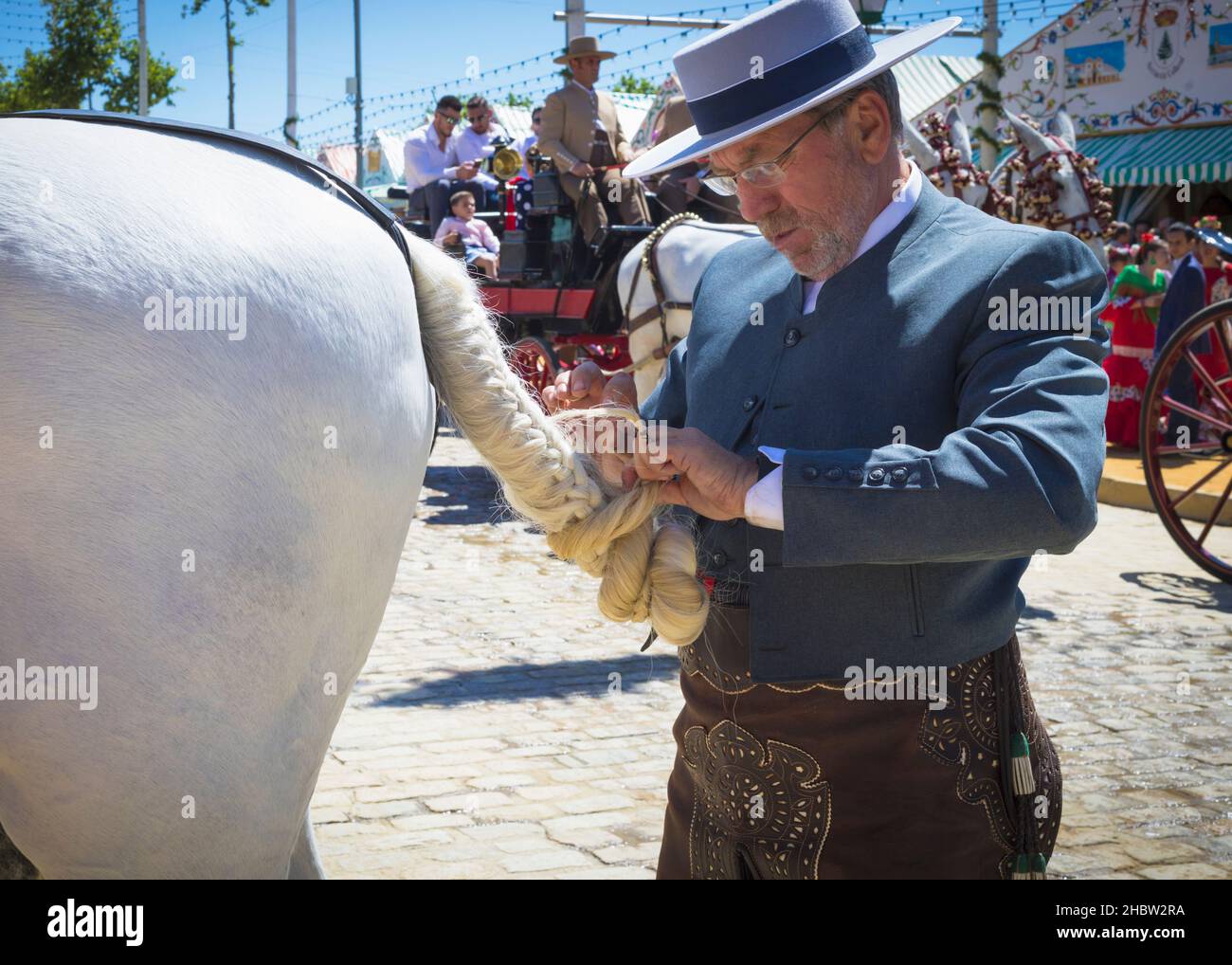 Séville, province de Séville, Andalousie, sud de l'Espagne.Feria de Abril, la foire d'avril.Homme dans le costume d'équitation traditionnel tressant et enroulant la queue Banque D'Images