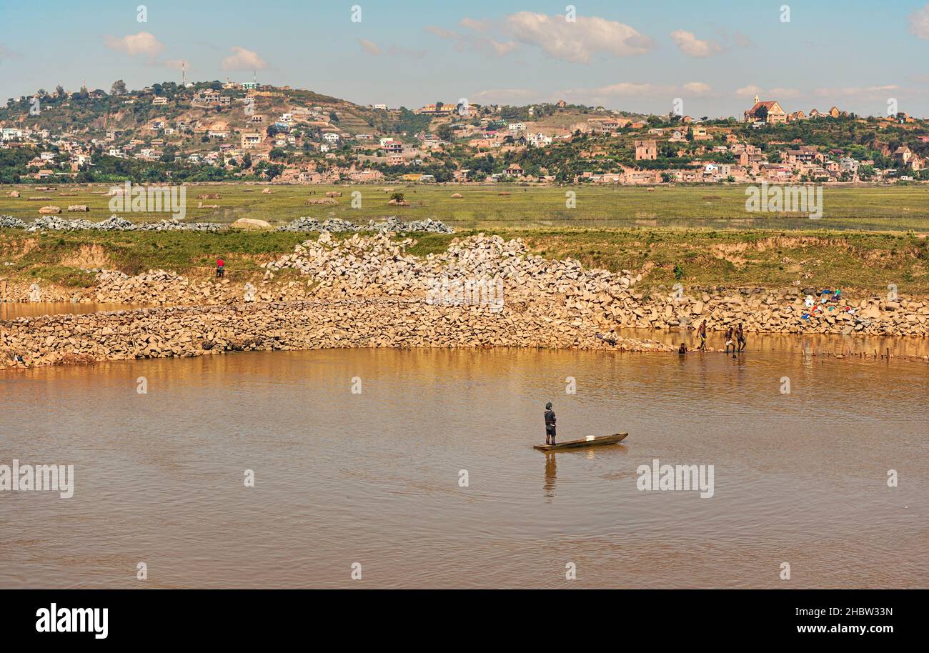Antananarivo, Madagascar - 07 mai 2019: Personnes travaillant près de la rivière le jour ensoleillé - pêche, faire de la lessive, faire des briques pour les maisons, les maisons à la colline dans Banque D'Images
