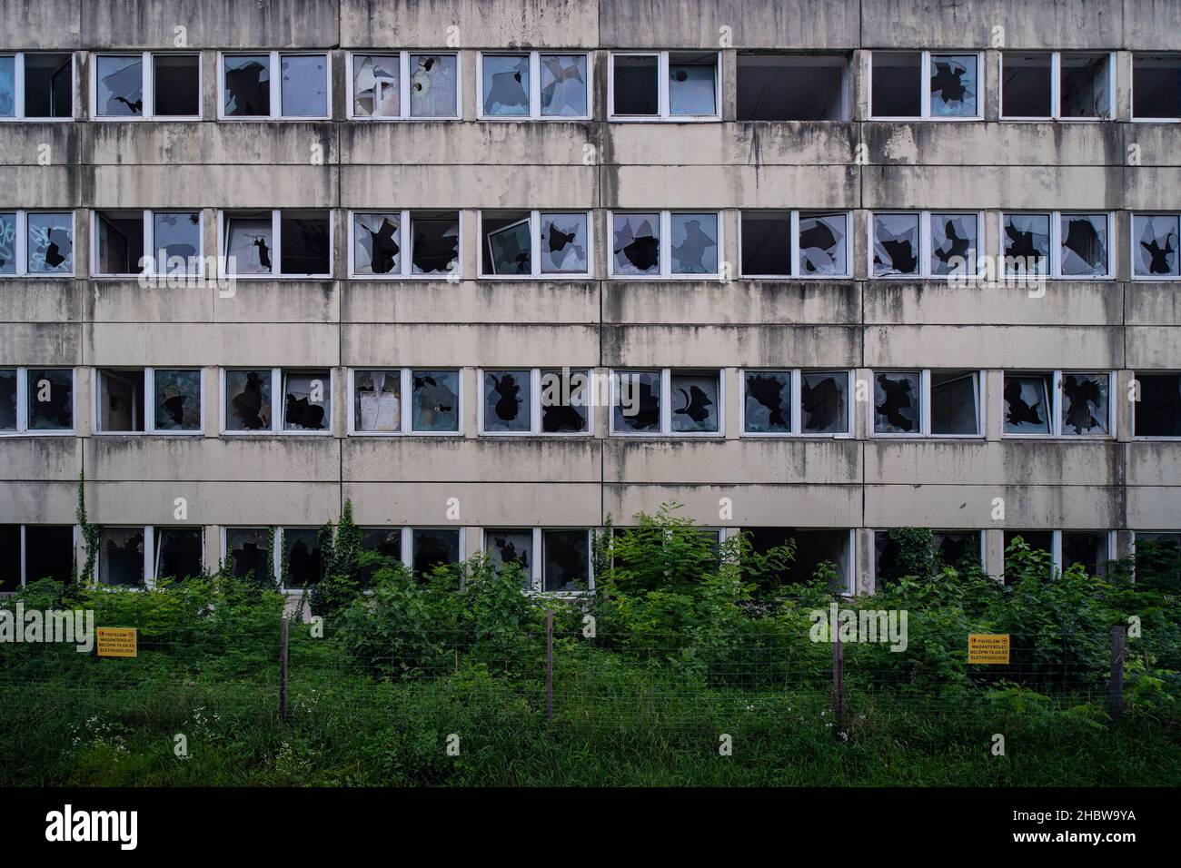 Bâtiment fantôme abandonné avec beaucoup de fenêtres cassées et de végétation non entretenue, papier peint oublié de barrack soviétique. Banque D'Images