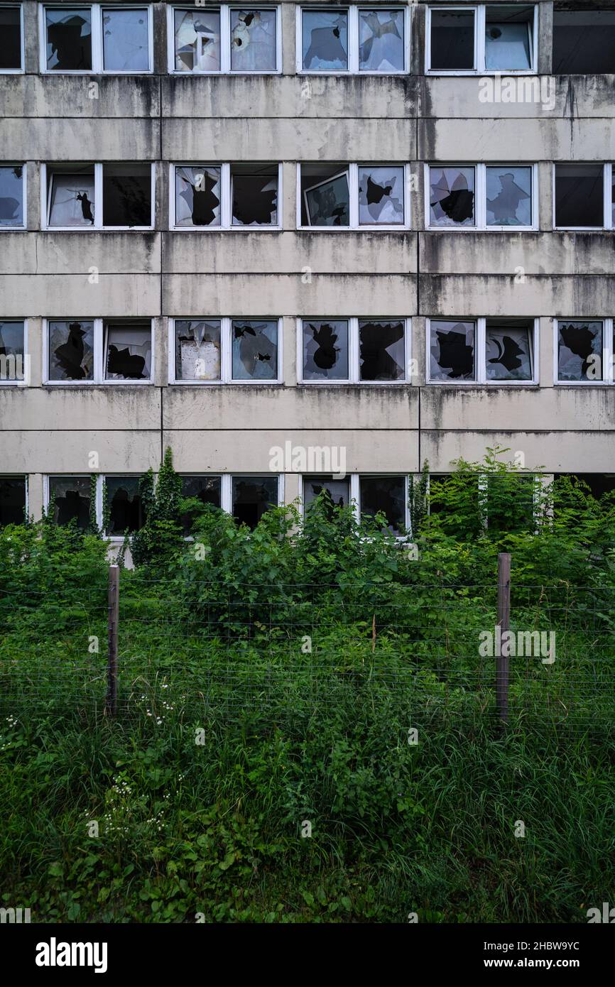 Bâtiment fantôme abandonné avec beaucoup de fenêtres cassées et de végétation non entretenue, papier peint oublié de barrack soviétique. Banque D'Images