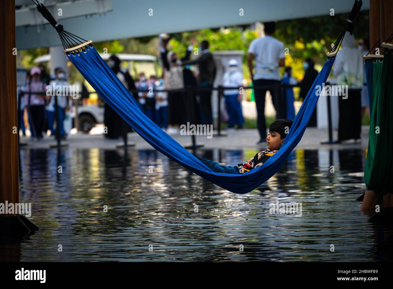 Dubai, Émirats Arabes Unis - 12.06.2021 : un jeune garçon indien se reposant dans un hamac bleu au-dessus de l'eau dans le pavillon du Brésil à l'exposition Dubai Expo 2020 Banque D'Images