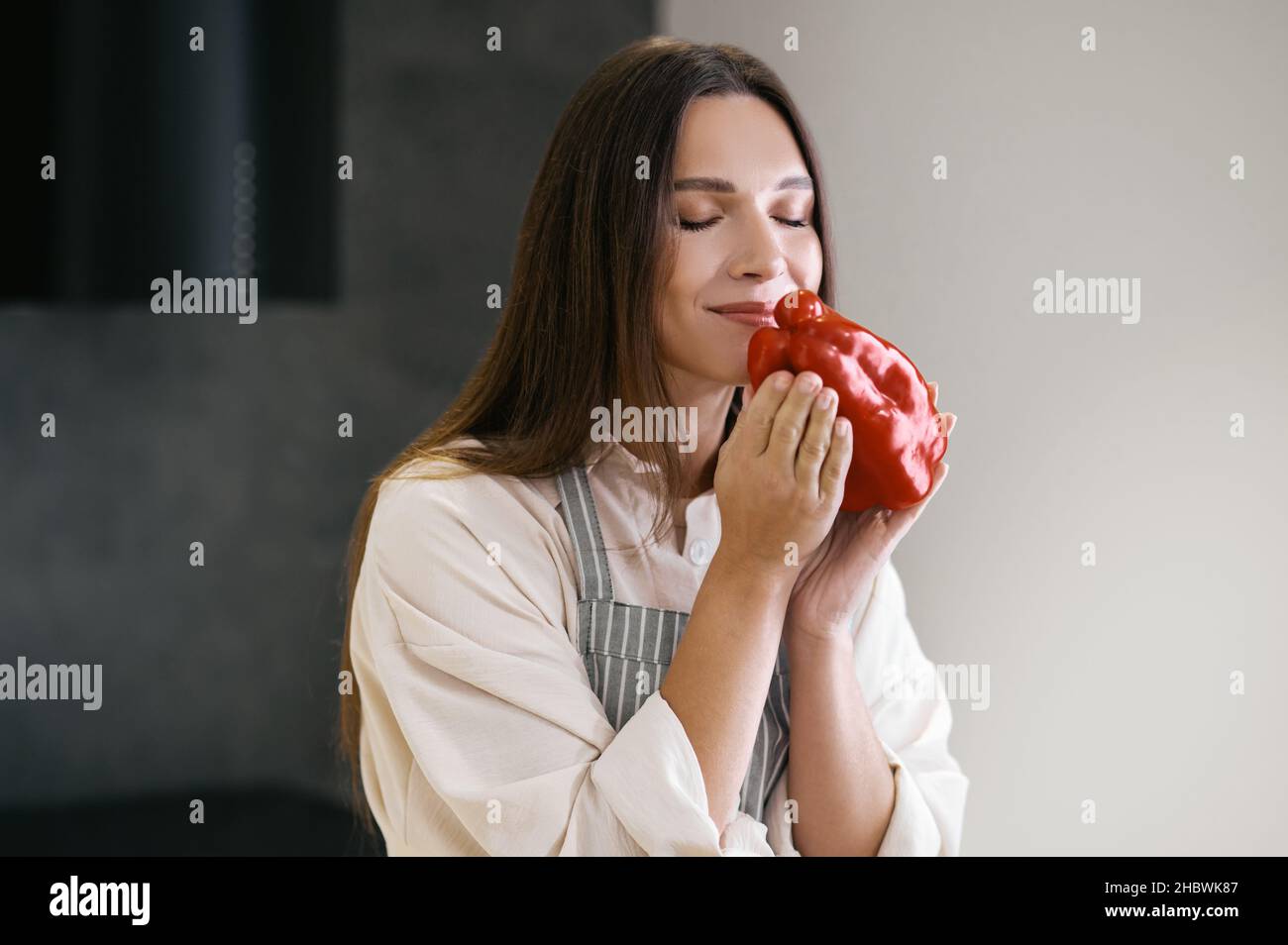Jeune femme aux cheveux longs tenant le poivron rouge dans les mains Banque D'Images
