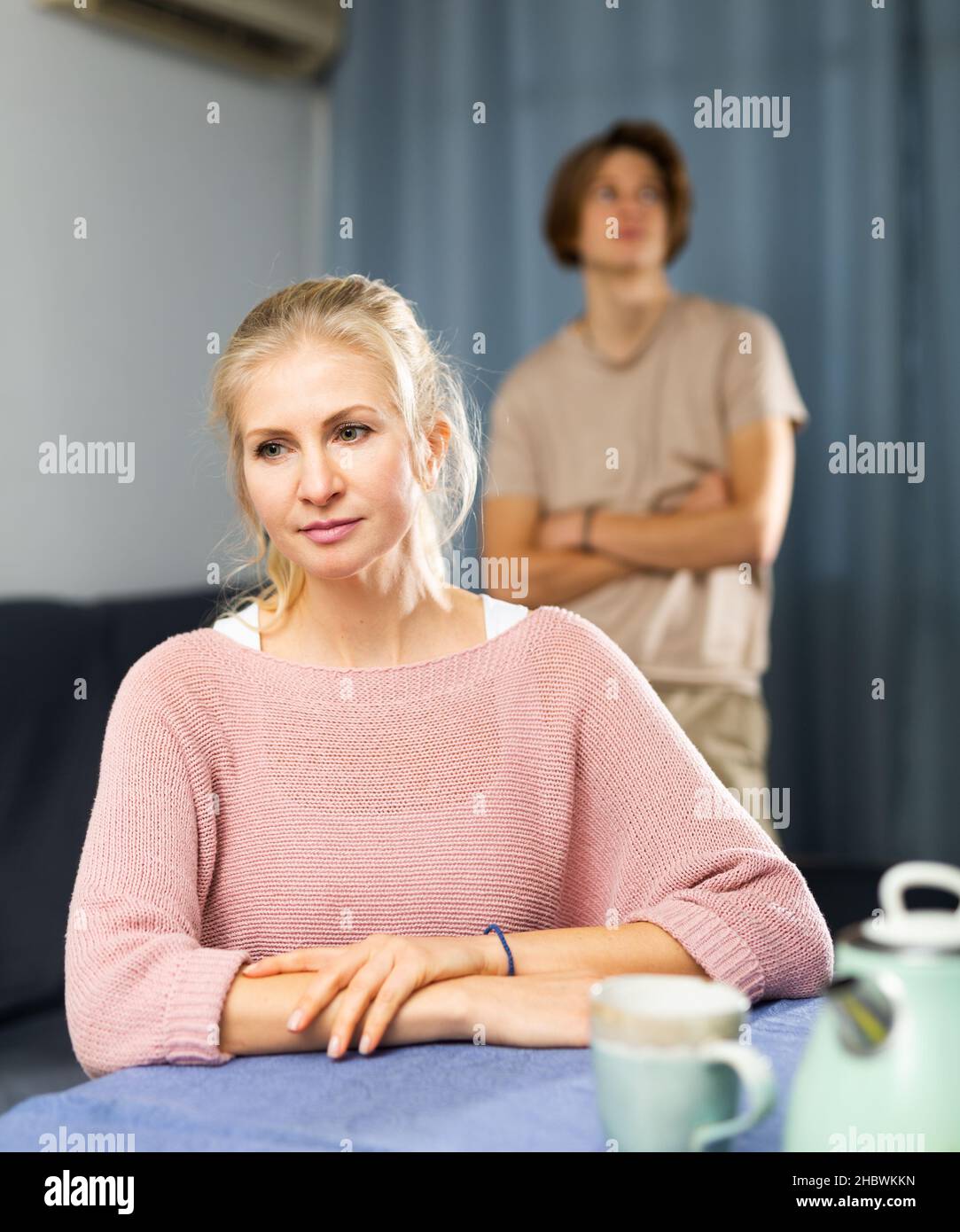 Femme contrariée assise à la table dans la cuisine Banque D'Images