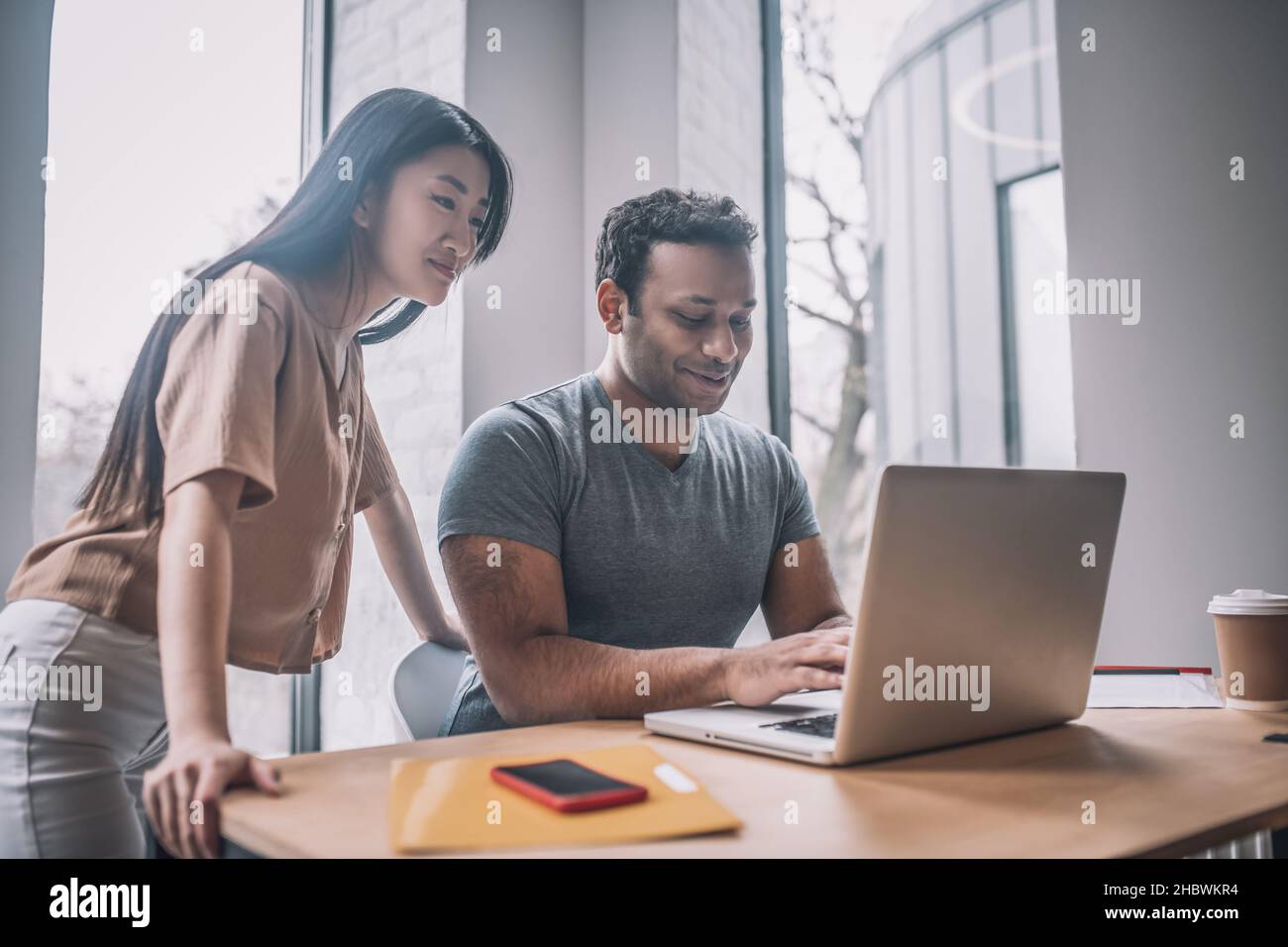 Un gars à la peau sombre à l'ordinateur portable et à regarder une fille asiatique Banque D'Images