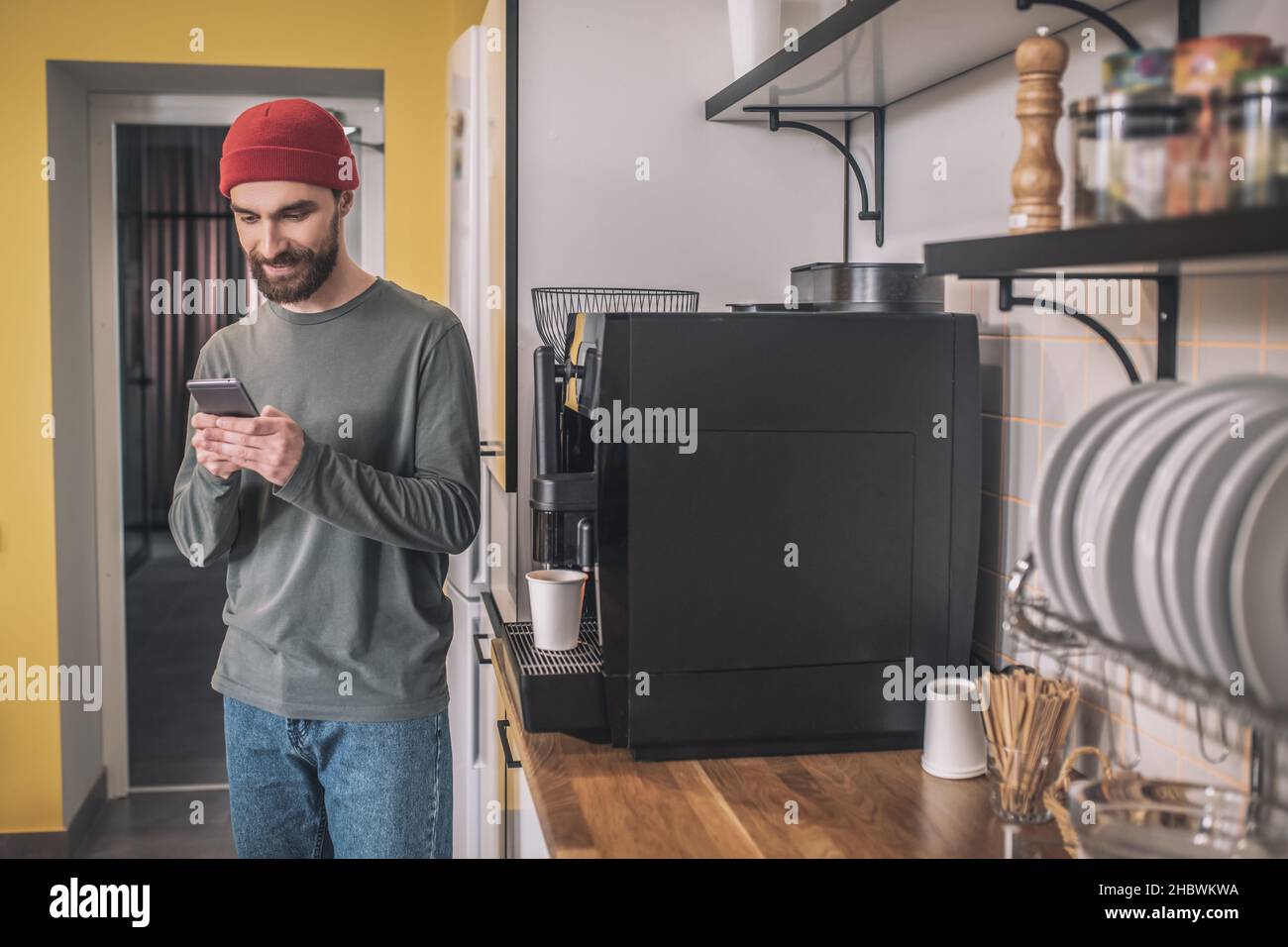 Homme regardant le smartphone près de la machine à café Banque D'Images