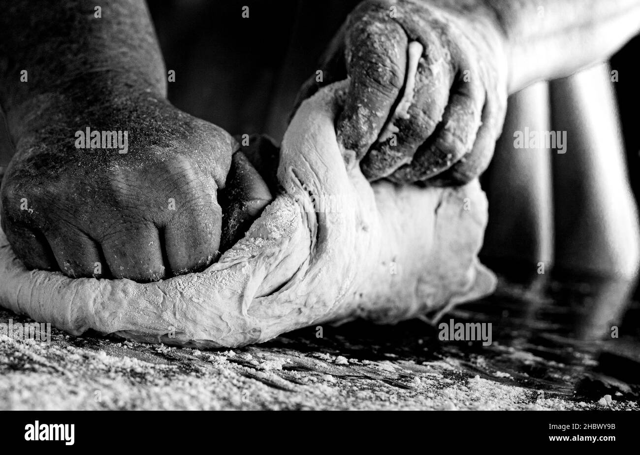 Les mains pétrissent la pâte sur une table pour préparer du pain frais fait maison. Banque D'Images