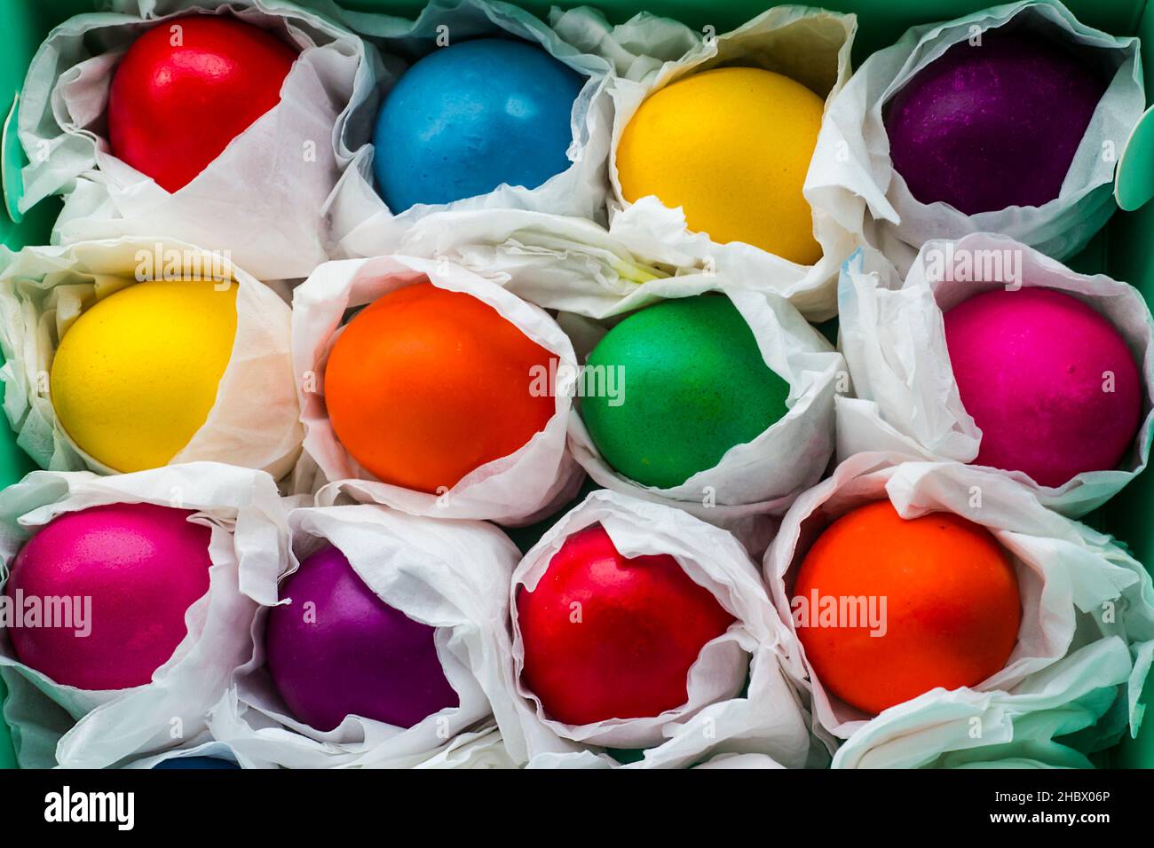 Œufs de Pâques colorés enveloppés dans du papier blanc dans la boîte de carton vert, background.Easter concept Banque D'Images