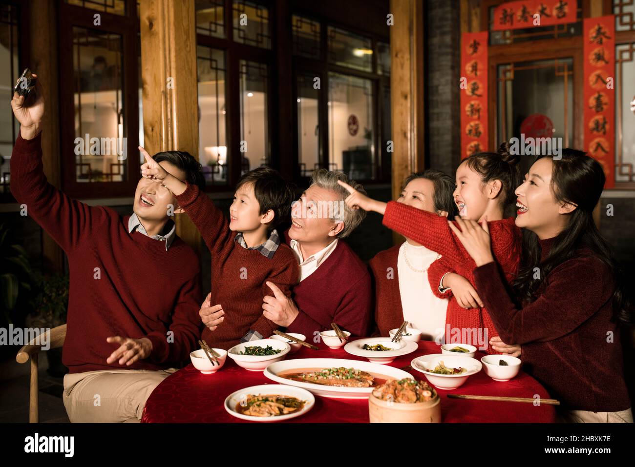 Des familles heureuses qui prennent des selfies avec leur téléphone mobile pendant le dîner de la Saint-Sylvestre Banque D'Images