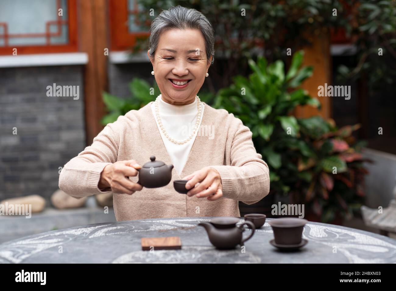 Une vieille femme qui boit du thé dans la cour Banque D'Images