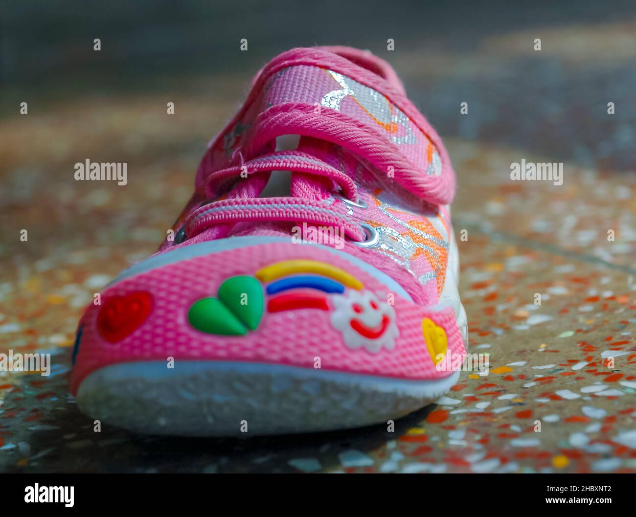 Photographie d'une petite profondeur de champ d'une chaussure décorative rose pour bébé sur un sol en béton poli. Banque D'Images