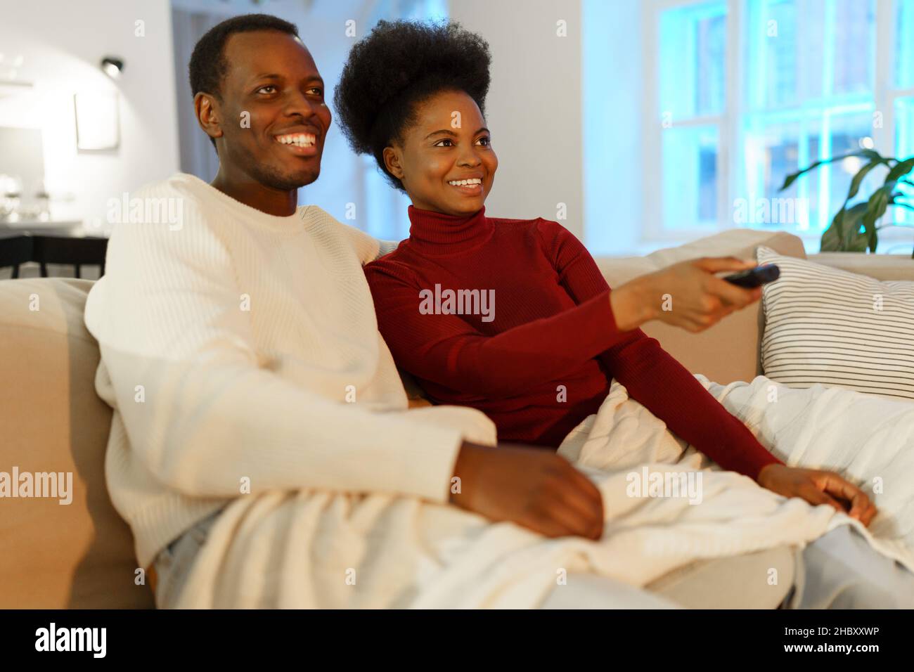 Jeune heureux afro famille américaine couple homme et femme regarder la comédie spectacle à la télévision et rire Banque D'Images