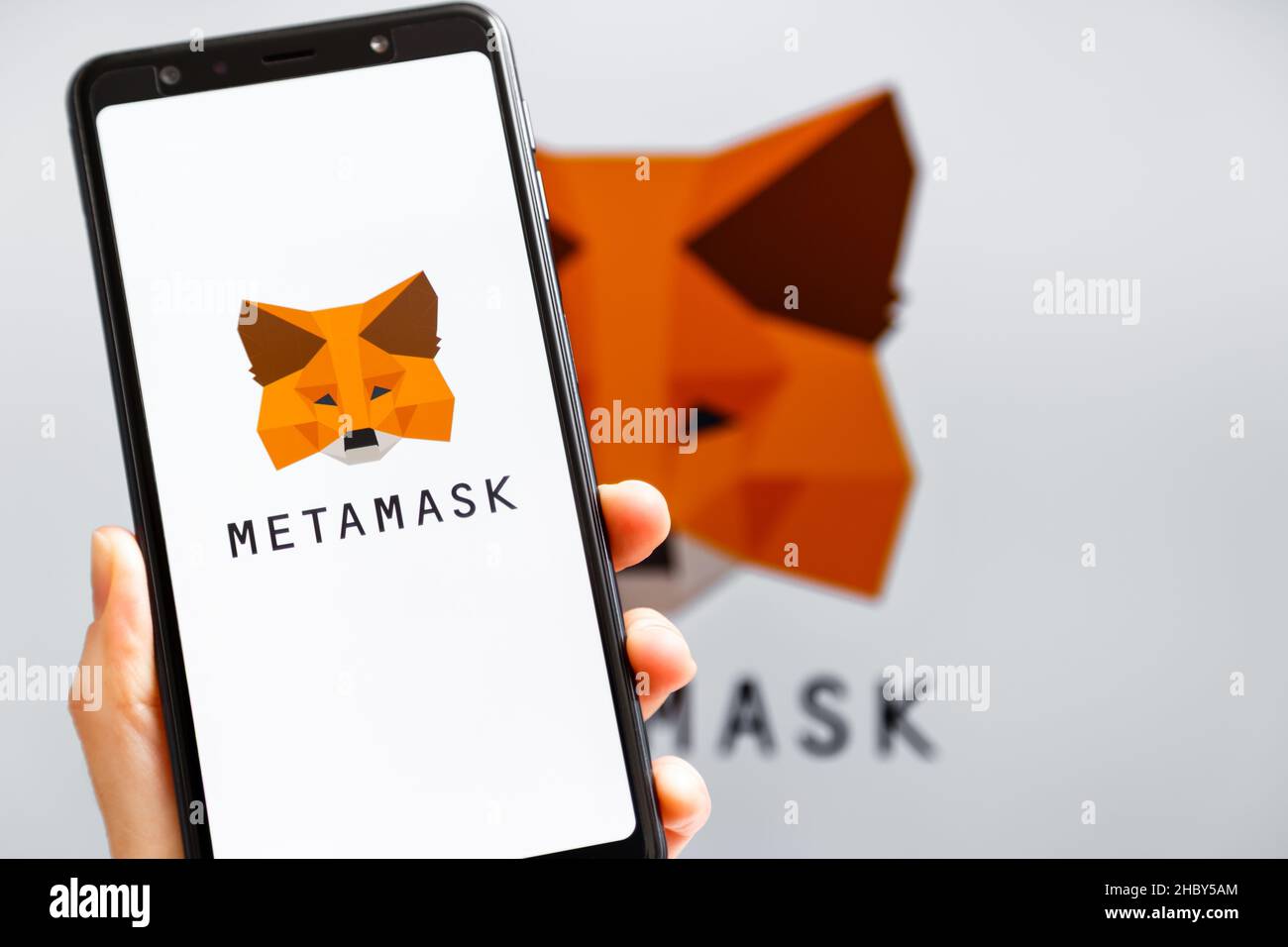 Ukraine, Odessa - octobre, 9 2021: Main tenant mobile avec l'application MetaMask fonctionnant à l'écran de smartphone avec le logo MetaMask en arrière-plan.MetaMask l'est Banque D'Images
