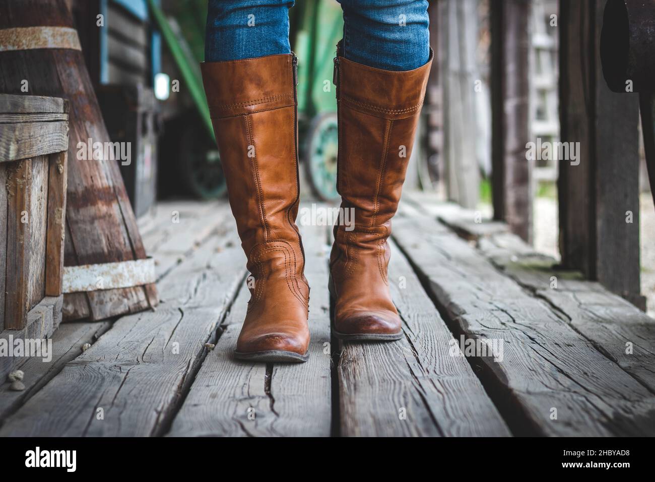Marche sur parquet avec des bottes en cuir sur le vieux ranch rétro.Style cow-boy. Banque D'Images