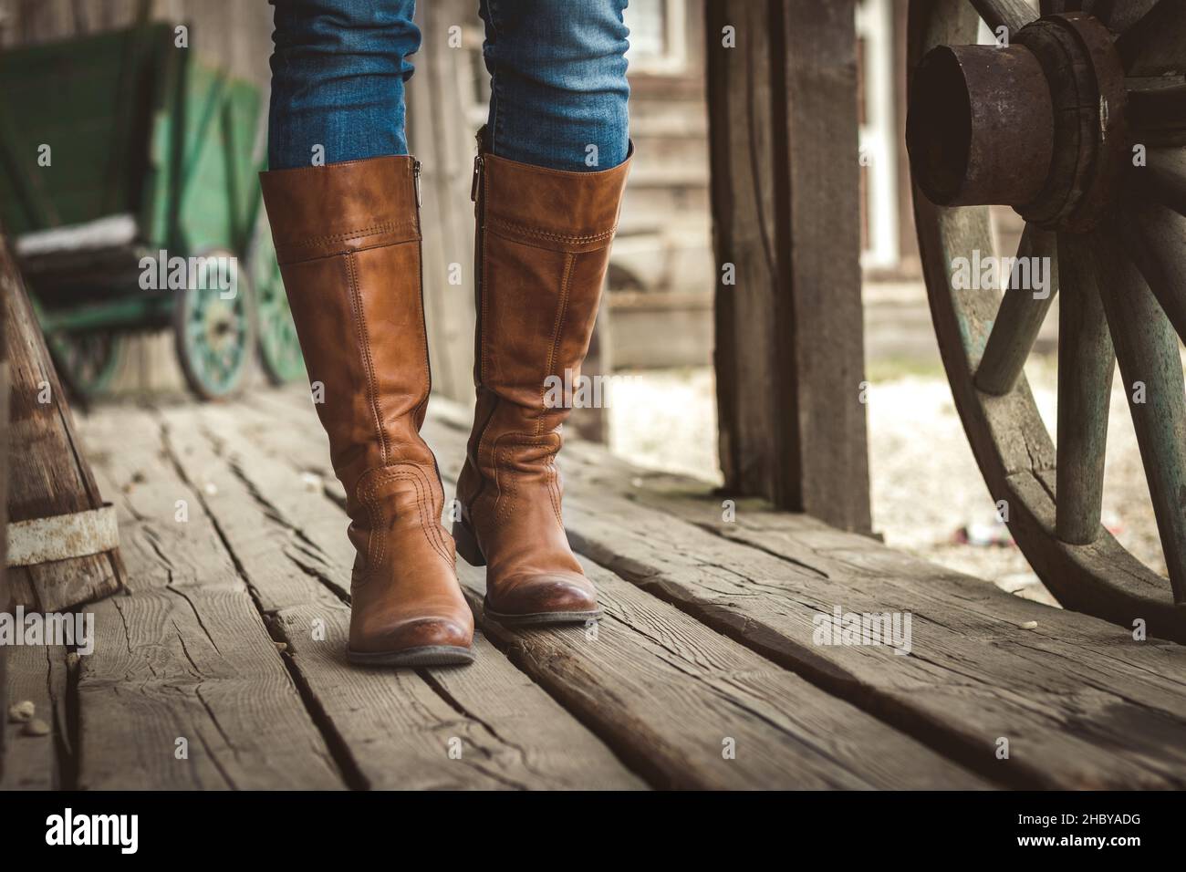 Marche sur parquet avec des bottes en cuir sur le vieux ranch rétro.Cow-boy de style vintage. Banque D'Images