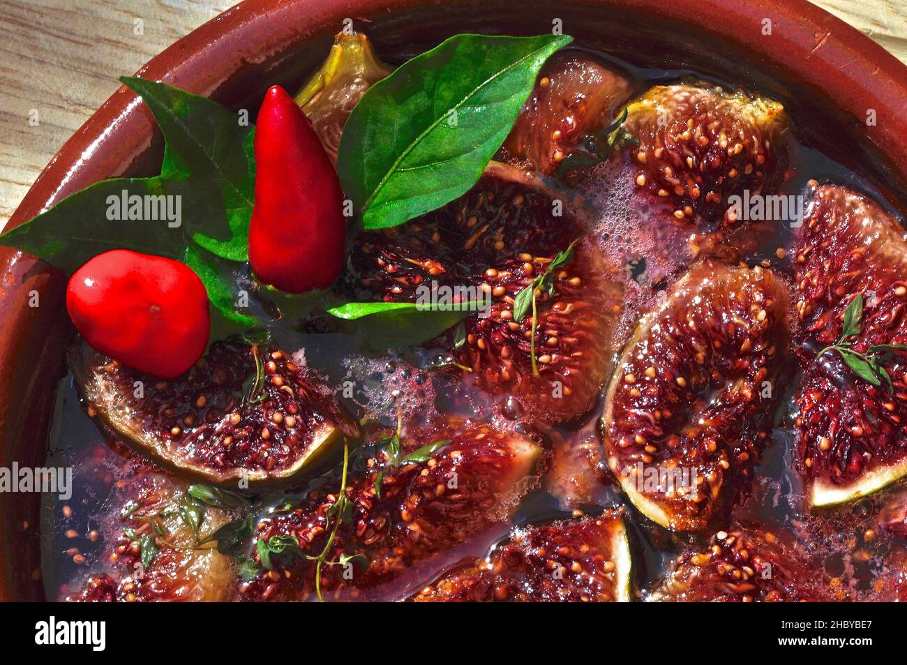 Figues cuites dans une casserole en faïence décorée de piments, vue de dessus Banque D'Images