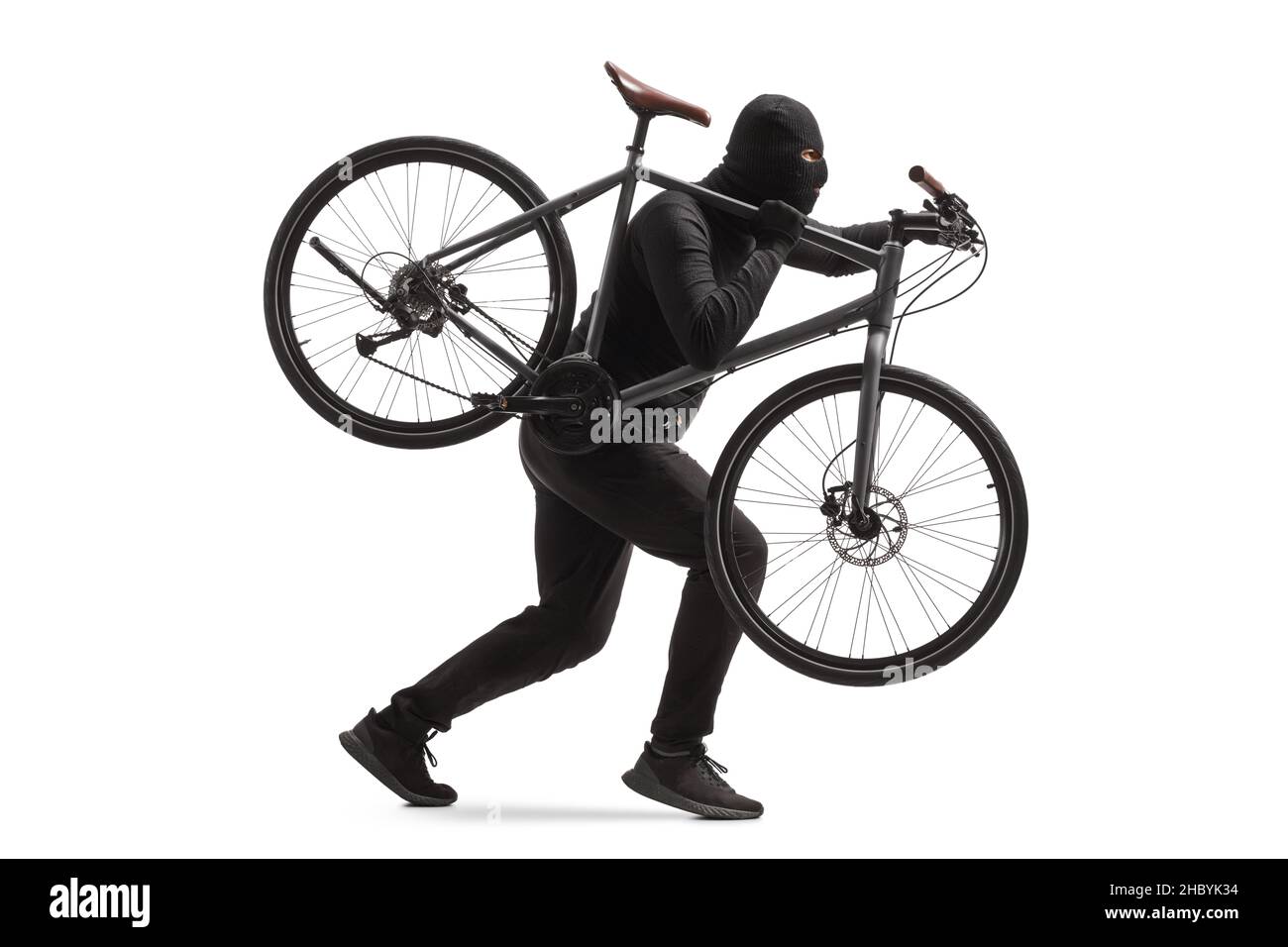 Plan de profil complet d'un cambrioleur dans des vêtements noirs avec une balaclava voler un vélo isolé sur fond blanc Banque D'Images